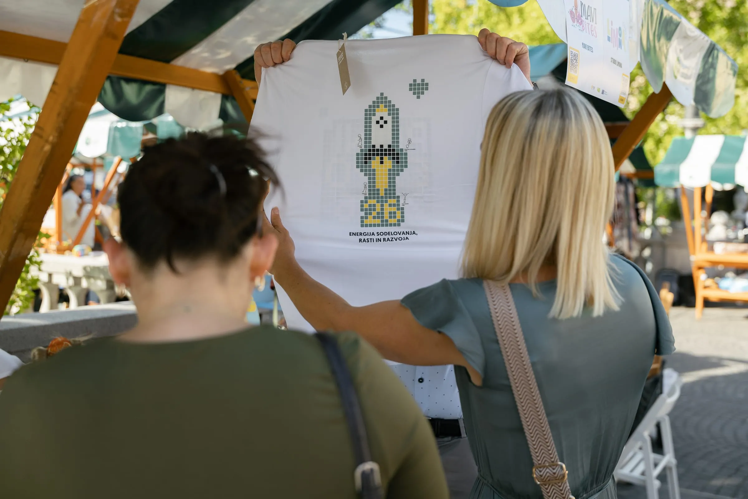 Obiskovalki si ogledujeta majico na stojnici
